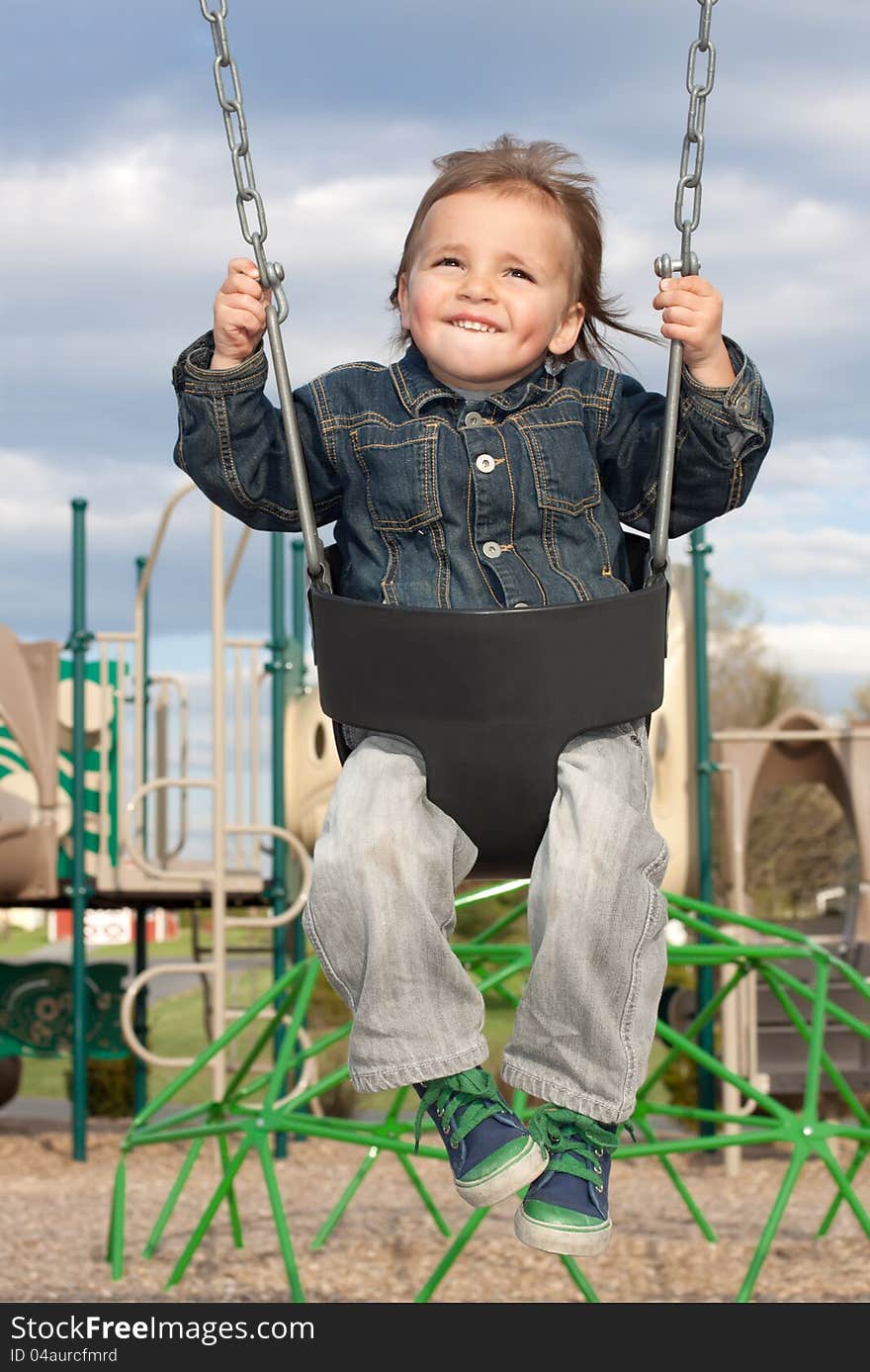 A young boy swinging at the playground on a beautiful spring day.