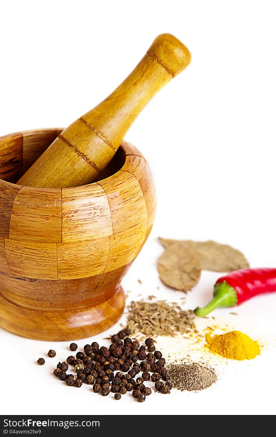 Mortar with pestle and variety of spices over white