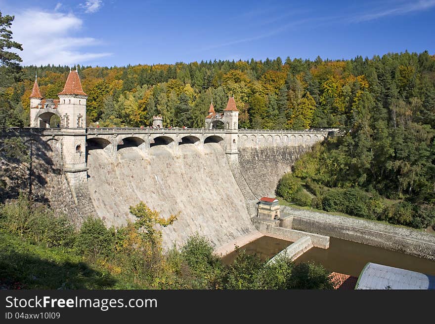 Waterworks on the river in the woods, dam in autumn sunny day with blue sky