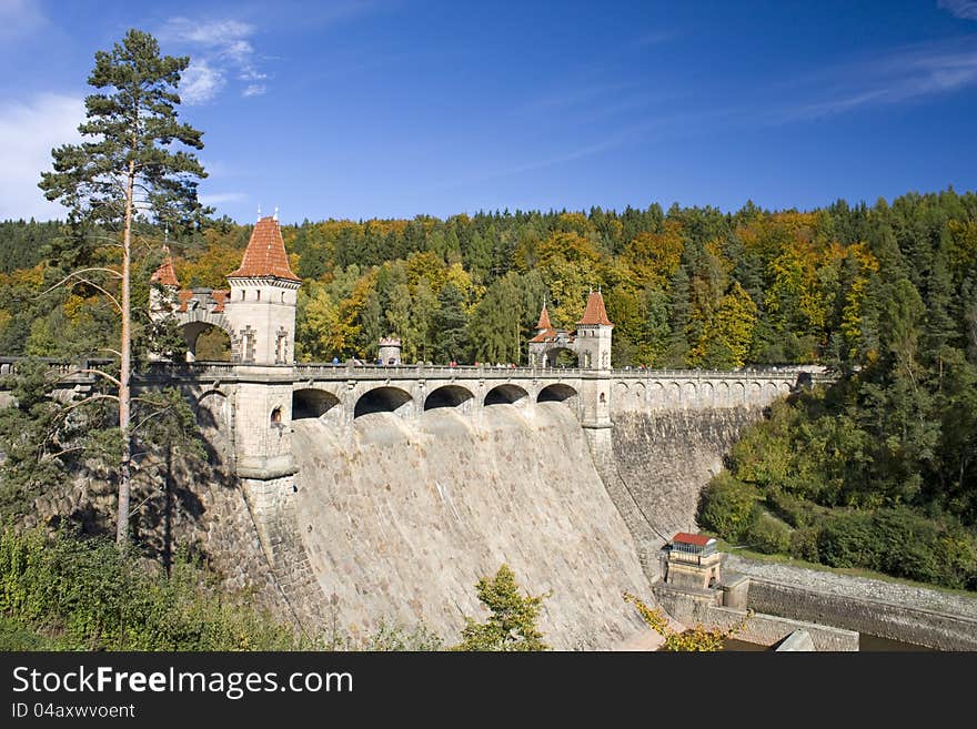 Stone dam in summer sunny day, water project status in forest landscape