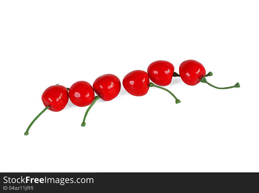 The red artificial cherries, lined in a row on a white background. The red artificial cherries, lined in a row on a white background