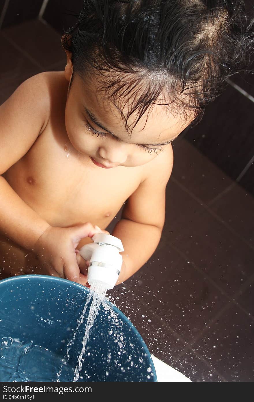 A little boy playing with water sprinkler in the bath room. A little boy playing with water sprinkler in the bath room.