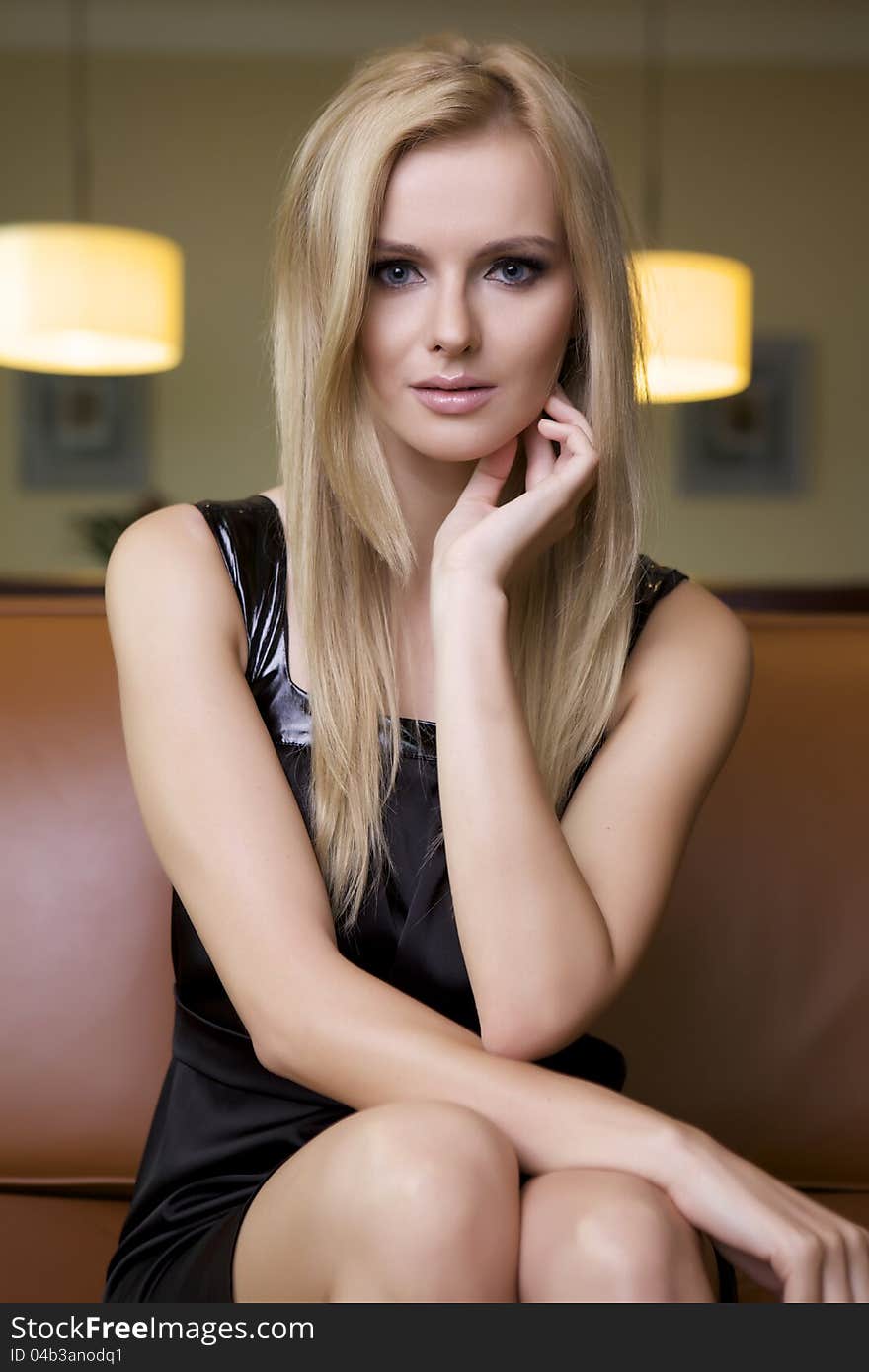 Attractive blond woman in black dress sitting on the couch