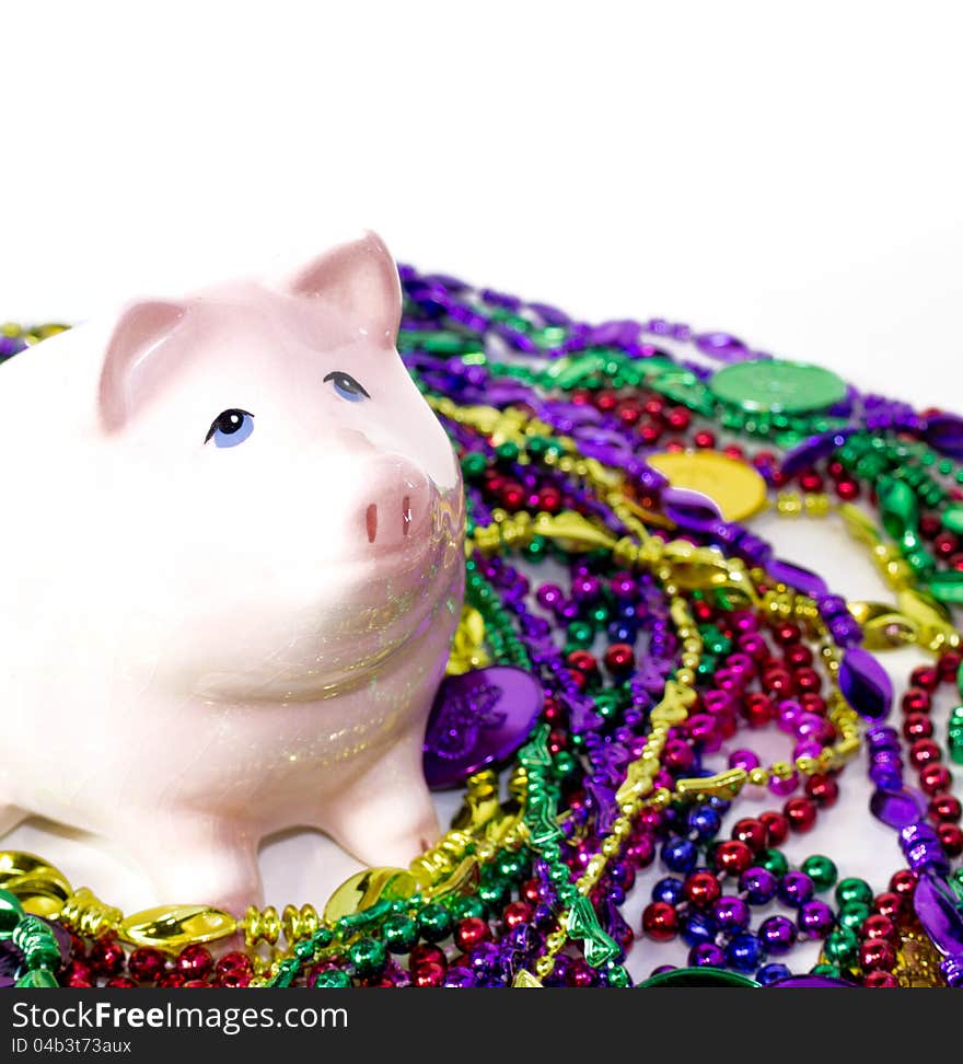 Pink piggy bank  with Mardi Gras colorful beads and coins. Pink piggy bank  with Mardi Gras colorful beads and coins