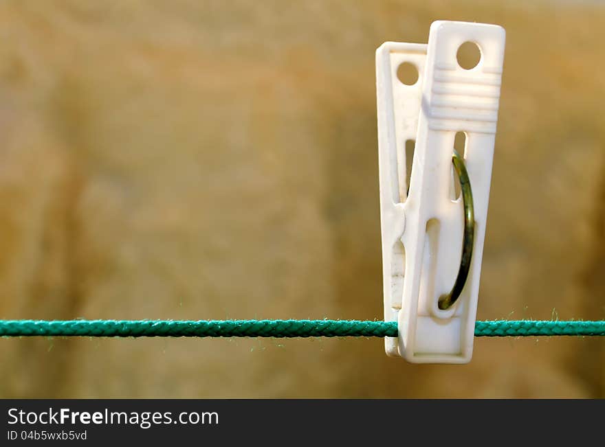 Clothespin hanging on a cord stretched the green, the background brown carpet. Clothespin hanging on a cord stretched the green, the background brown carpet