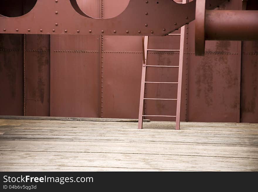 Red metal ladder inside the ship, metal structure with wooden floor. Red metal ladder inside the ship, metal structure with wooden floor