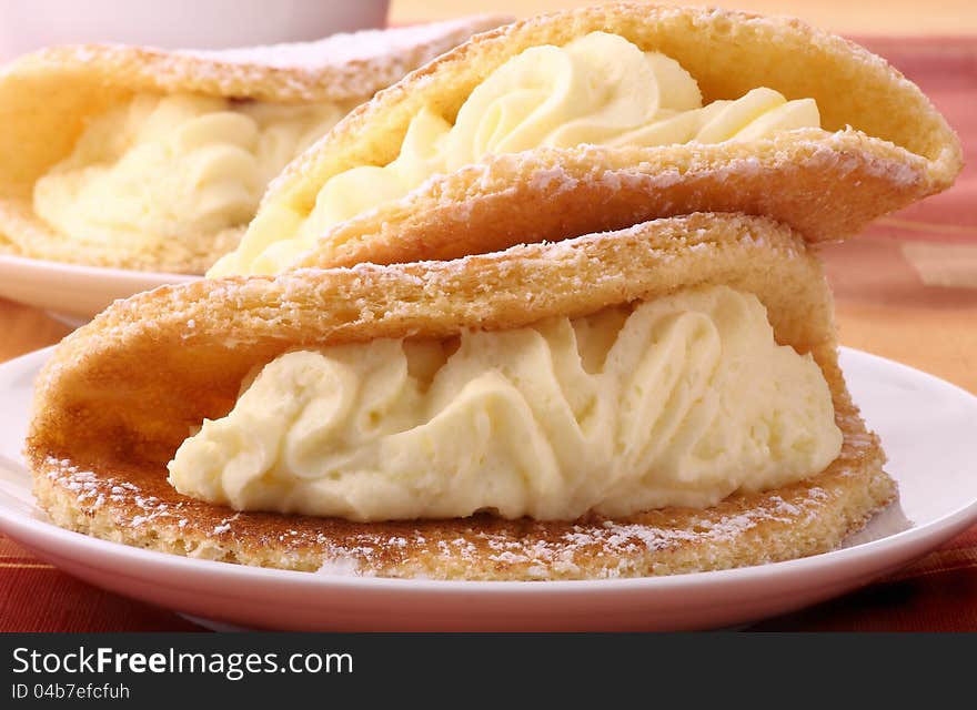 Cream cakes in the shape of omelets on plates. Cream cakes in the shape of omelets on plates