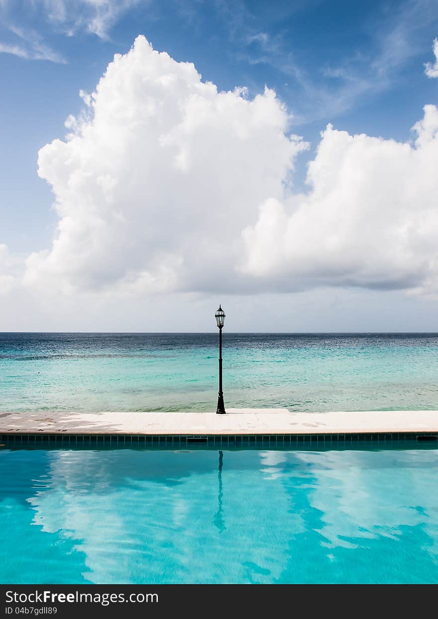 Unusual seascape with a lamp, crystal clear water and a deep blue sky with a big cloud.