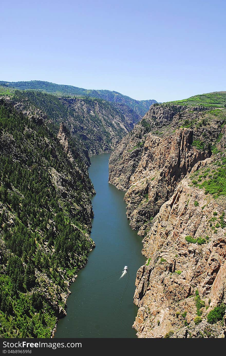 A boat travels up the Gunnison Gorge in the Colorado Mountains. A boat travels up the Gunnison Gorge in the Colorado Mountains