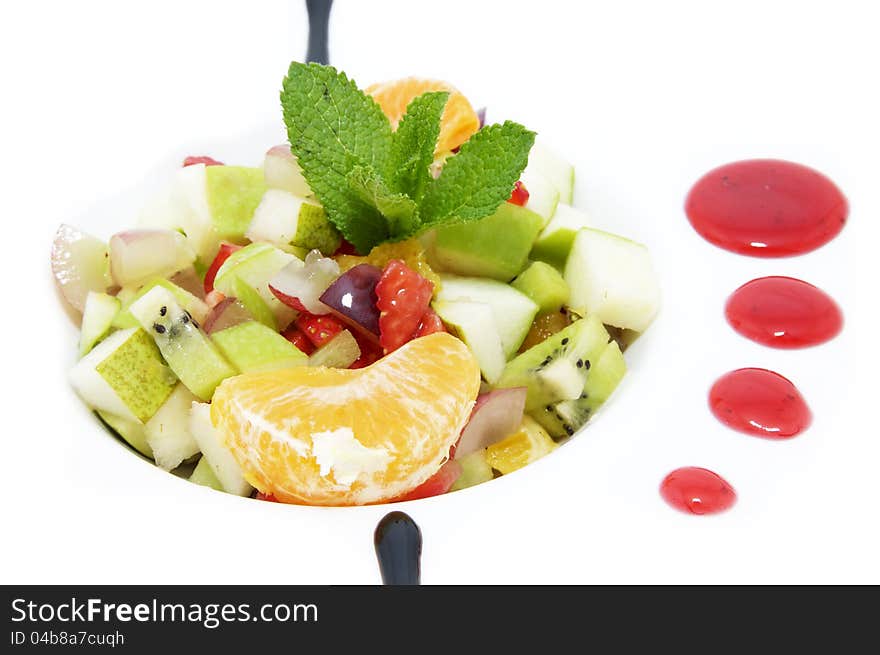 Fruit salad decorated with mint on a white plate. Fruit salad decorated with mint on a white plate