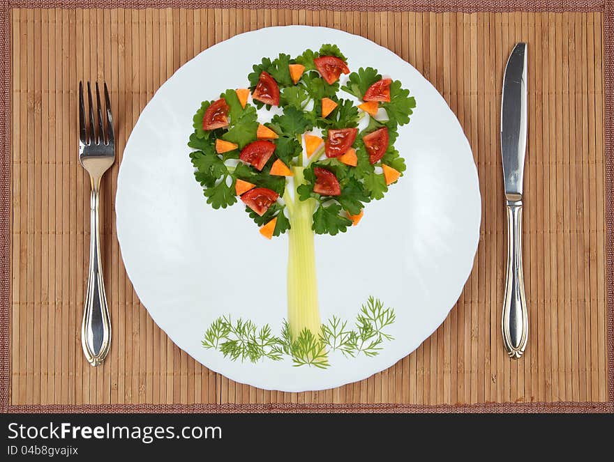 Tree of parsley and celery stalks with a lawn grass and fruit on a plate