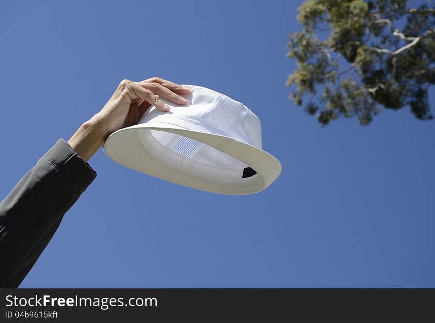 White hat held up in the air in one hand. White hat held up in the air in one hand