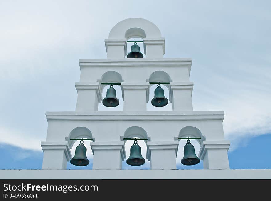 Six metal bells at the wall with cloudy sky