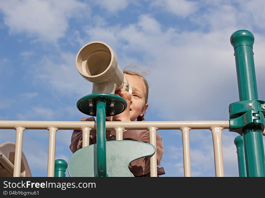 A young girl looks through a telescope at the playground. A young girl looks through a telescope at the playground.