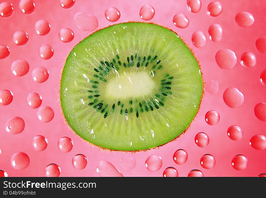 A fresh slice of kiwi fruit in red background drops.