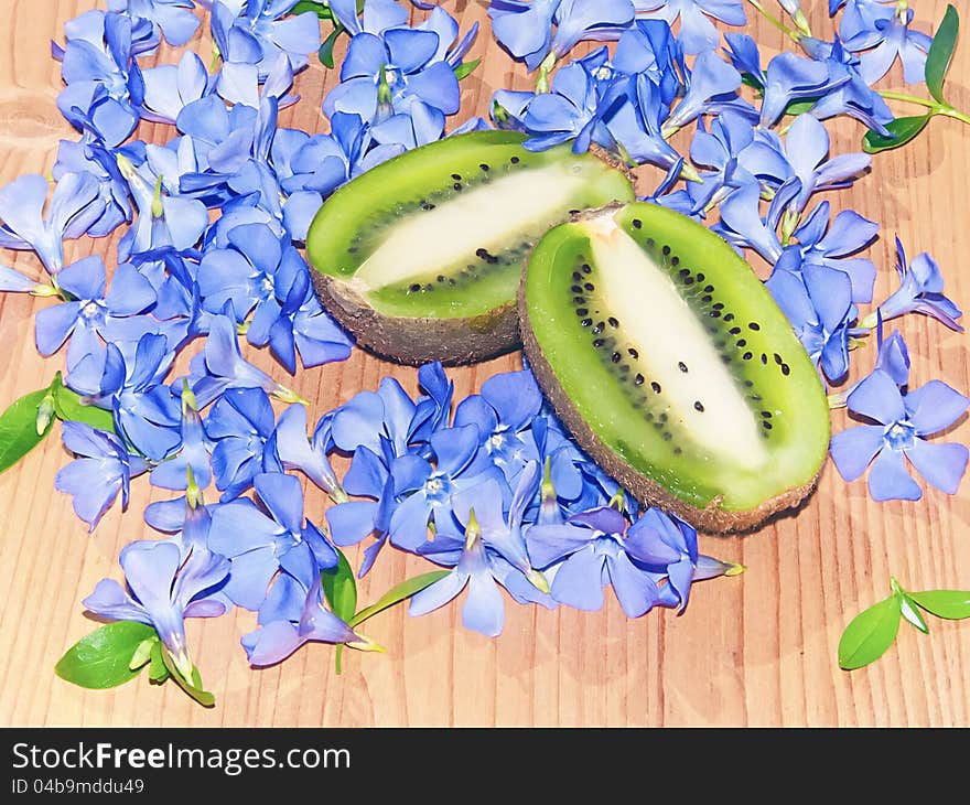 Halved juicy kiwi fruit and lots of blue flower. Halved juicy kiwi fruit and lots of blue flower