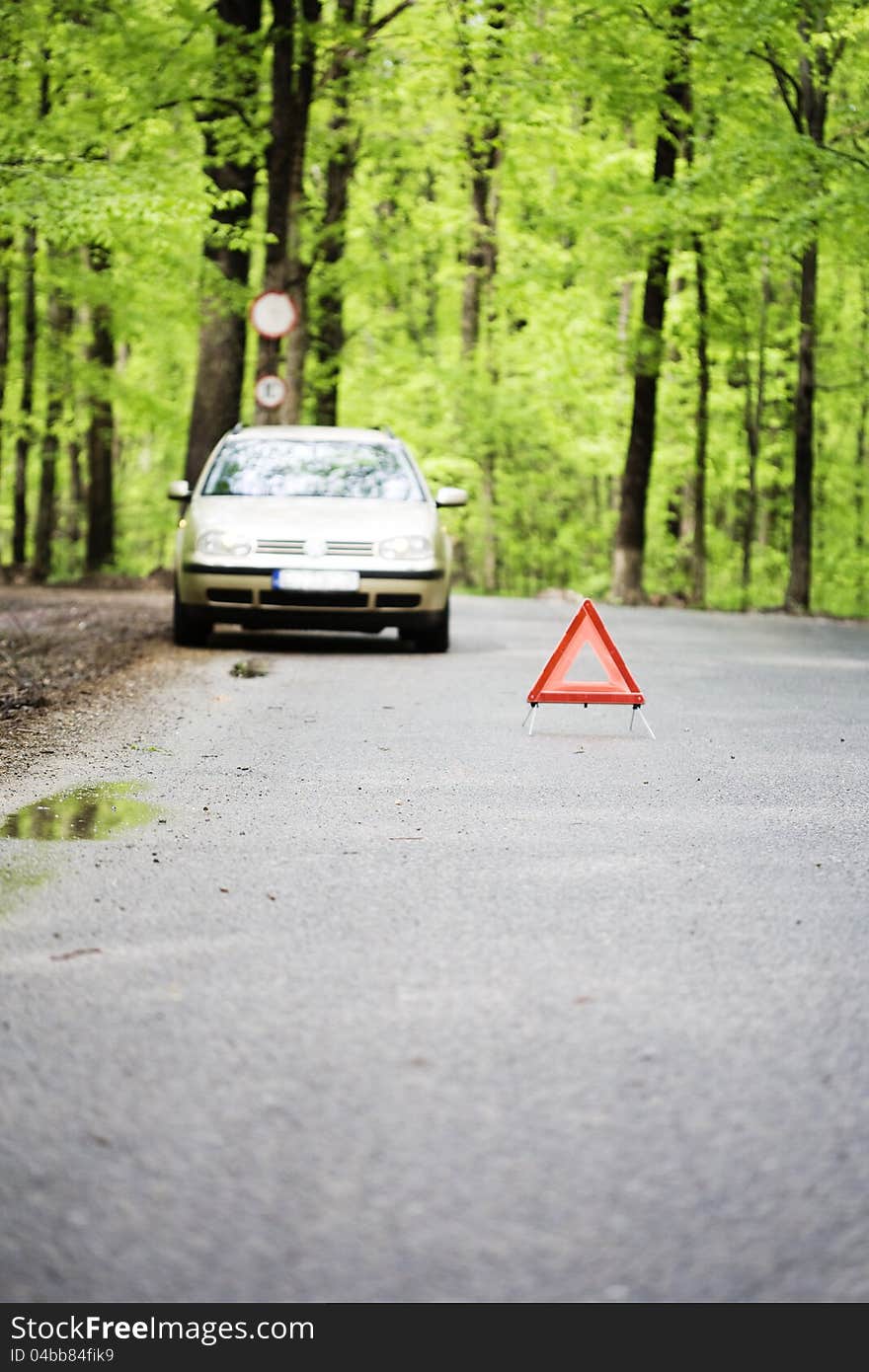 Stopped car in  the woods  with  a warning triangle in front. Stopped car in  the woods  with  a warning triangle in front