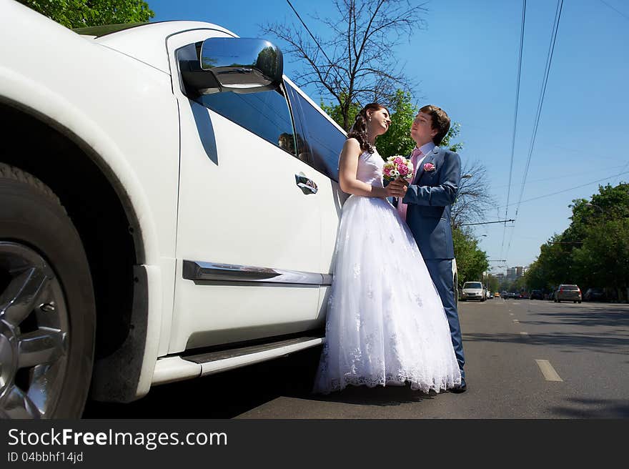 Happy bride and groom about wedding limousine