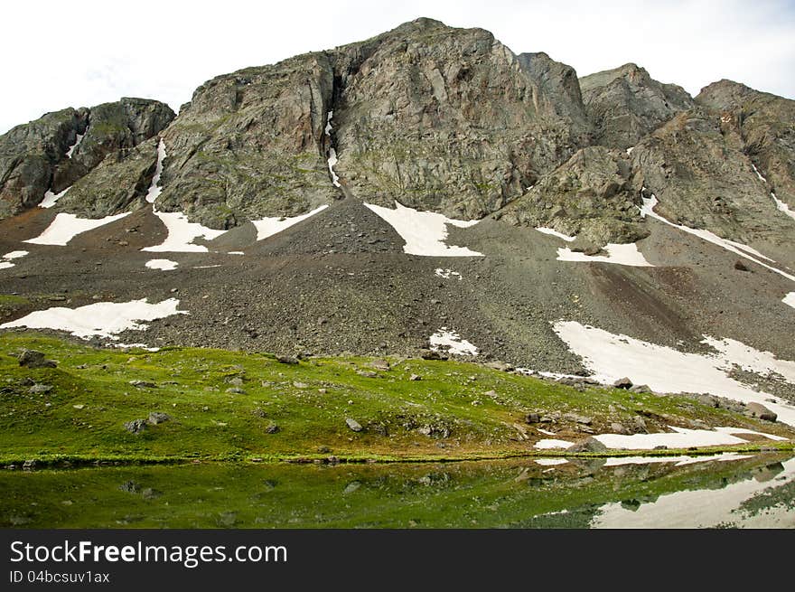 Melting snow and water reflections in a mountain lake. Melting snow and water reflections in a mountain lake.