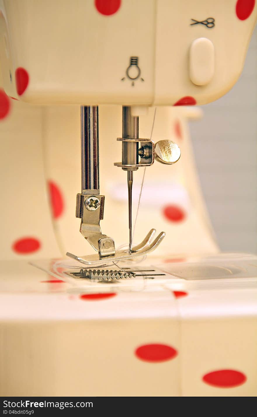 Close up photo of a modern electric sewing machine with a red polka dot design. Close up photo of a modern electric sewing machine with a red polka dot design.