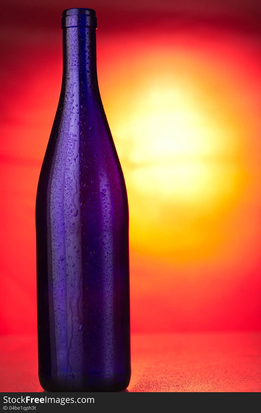 Opened blue glass bottle on sunset background