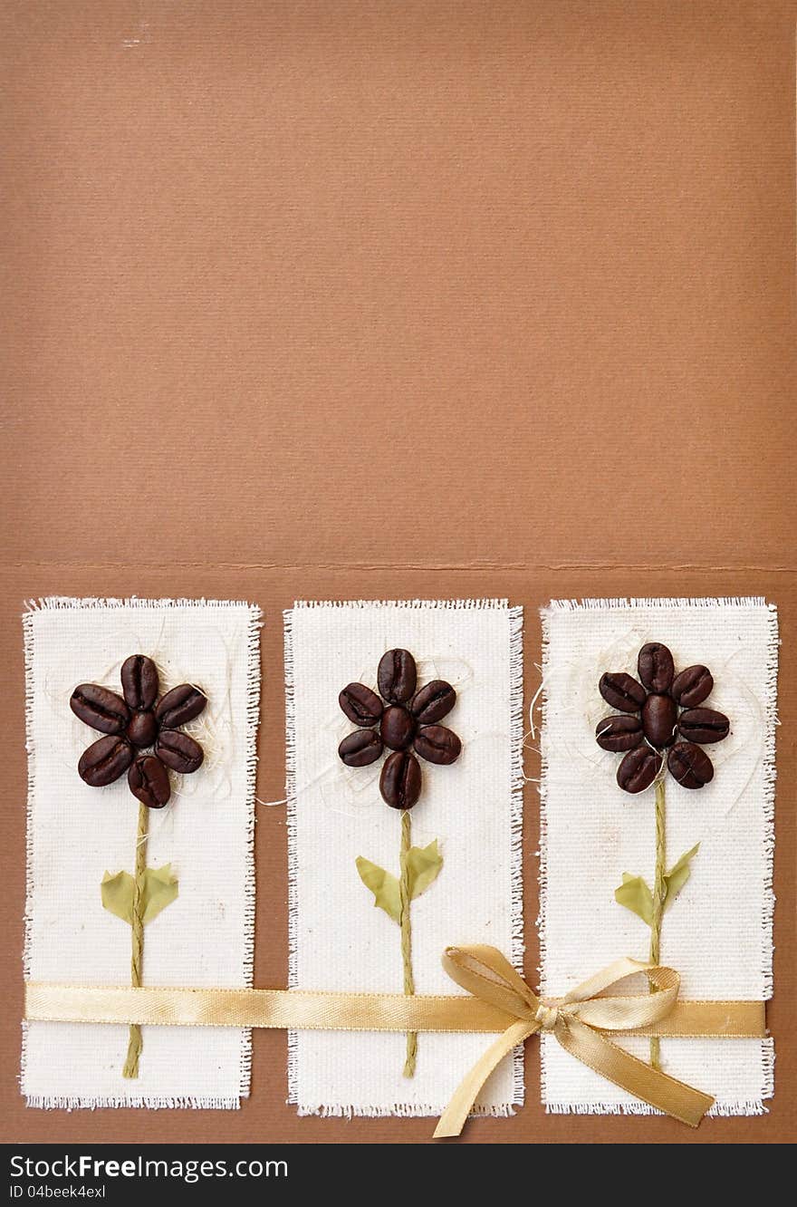 Handmade paper card with coffee beans flower design and a bow. Album book cover abstract background.