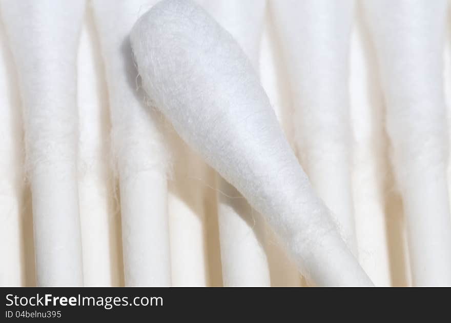 A photograph of a single cotton swab on a background of multiple cotton swabs