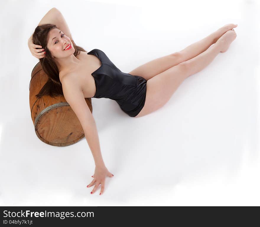 A vintage pinup inspired image of a gorgeous young woman in a sexy retro swimsuit, leaning on a barrel and smiling at the viewer. A vintage pinup inspired image of a gorgeous young woman in a sexy retro swimsuit, leaning on a barrel and smiling at the viewer