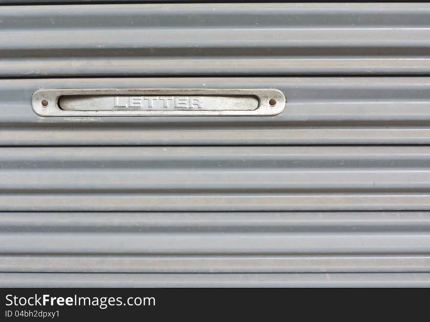 Letter slot on gray metal stripe pattern in close up view. Letter slot on gray metal stripe pattern in close up view