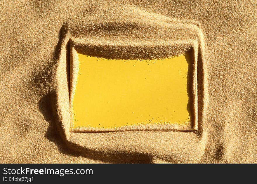 Closeup of blank yellow paper sheet on sand surface. Closeup of blank yellow paper sheet on sand surface