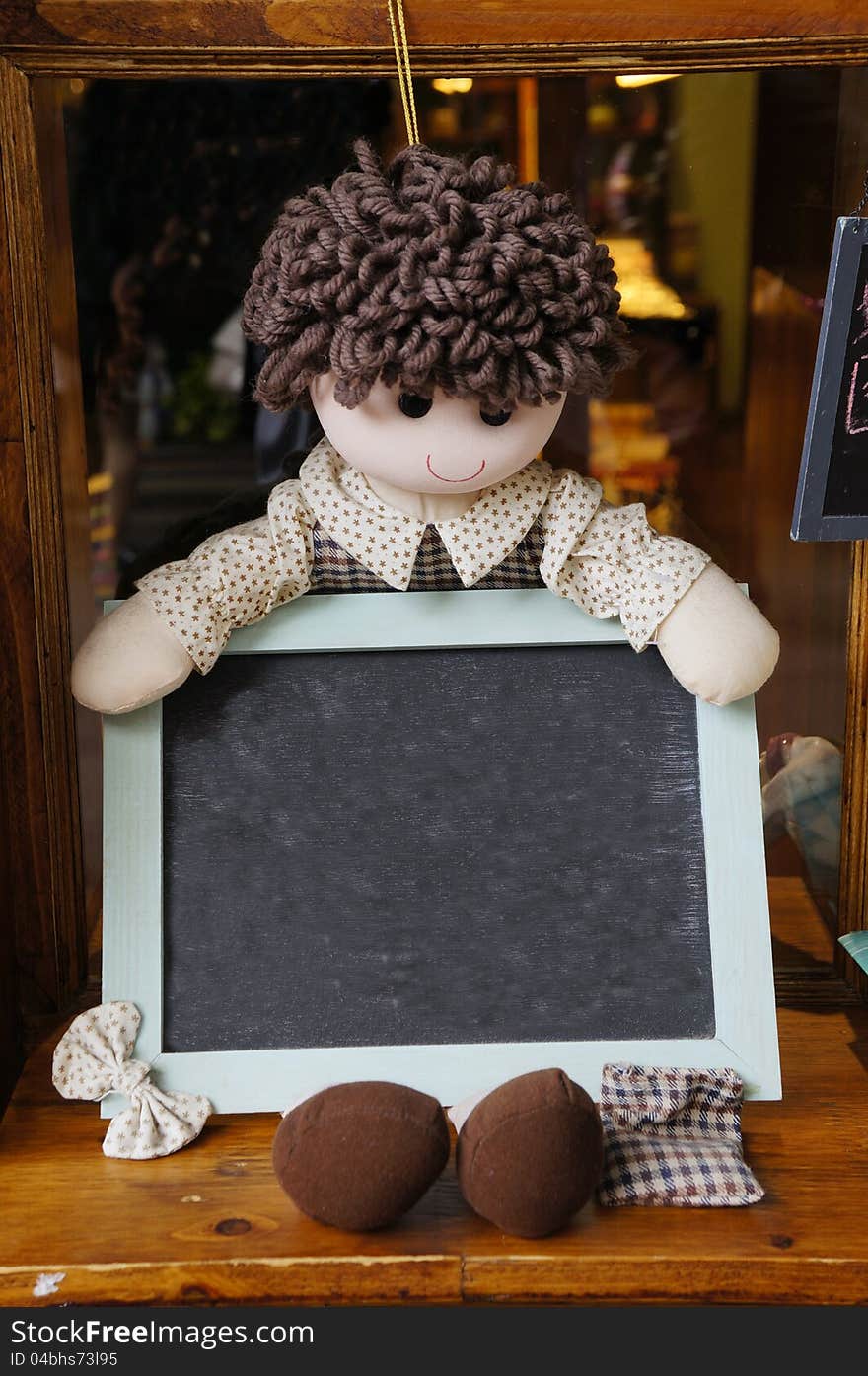 A rag doll holding a blank blackboard. A rag doll holding a blank blackboard.