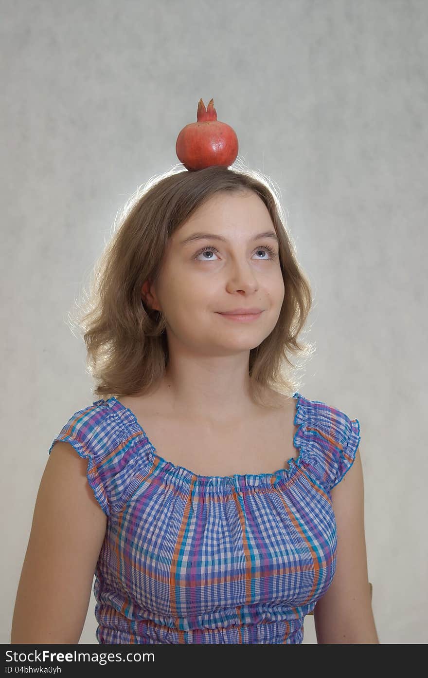 Girl holding pomegranate on her head. Girl holding pomegranate on her head