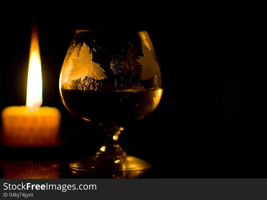 Glass of wine and burning candle on black background. Glass of wine and burning candle on black background