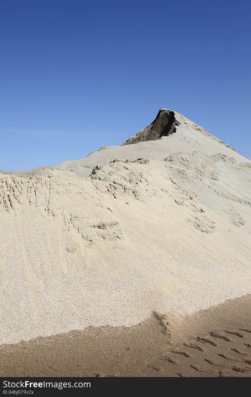 Grey sand mound and clear blue sky