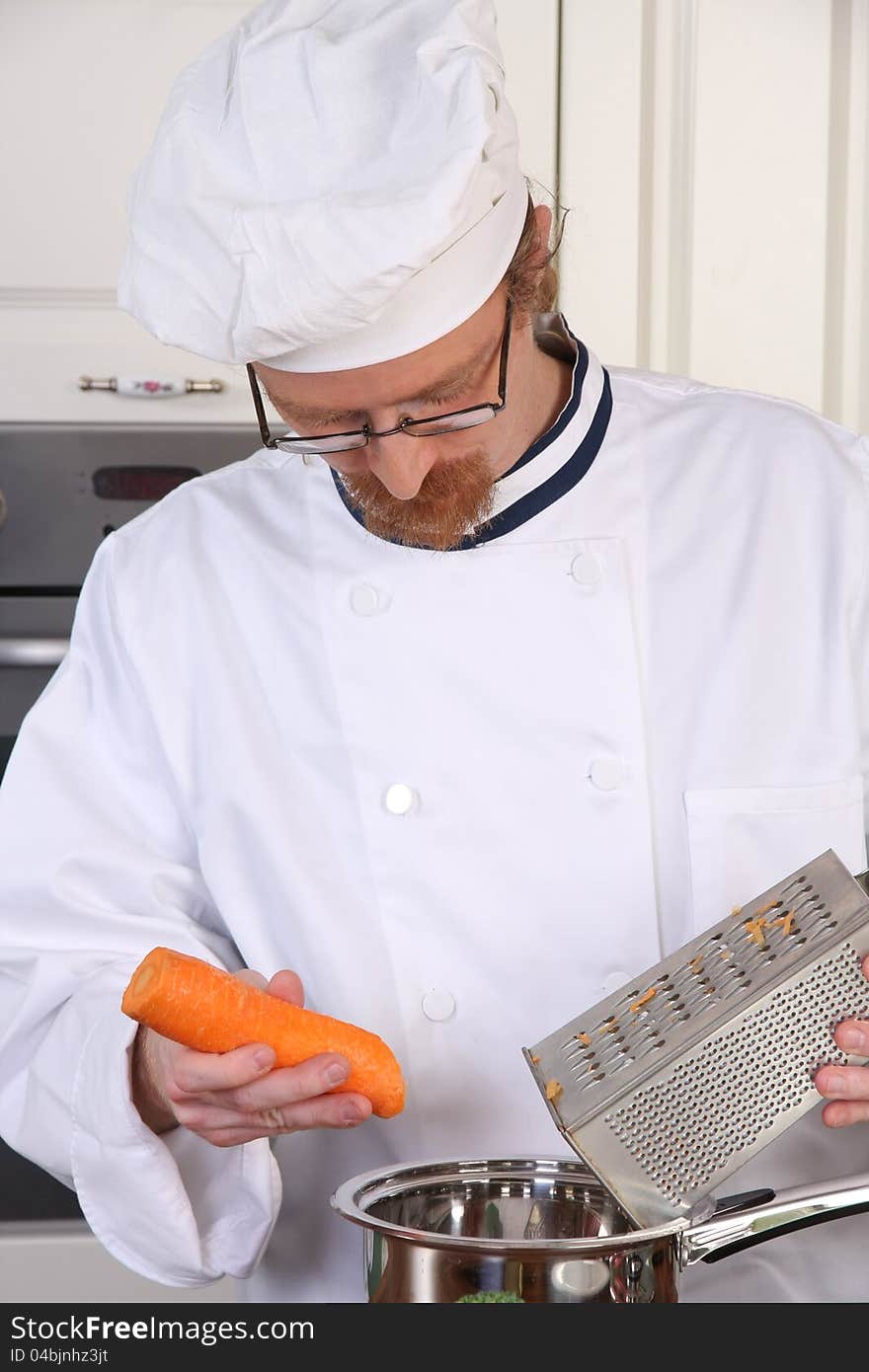 Young chef with carrot, preparing lunch in kitchen. Young chef with carrot, preparing lunch in kitchen