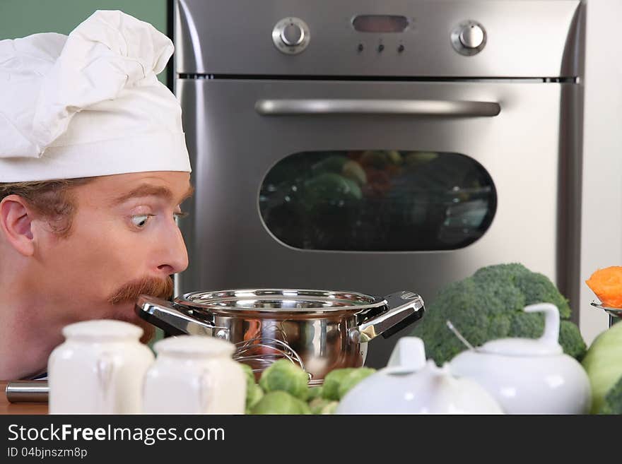 Funny young chef strange looking at pot