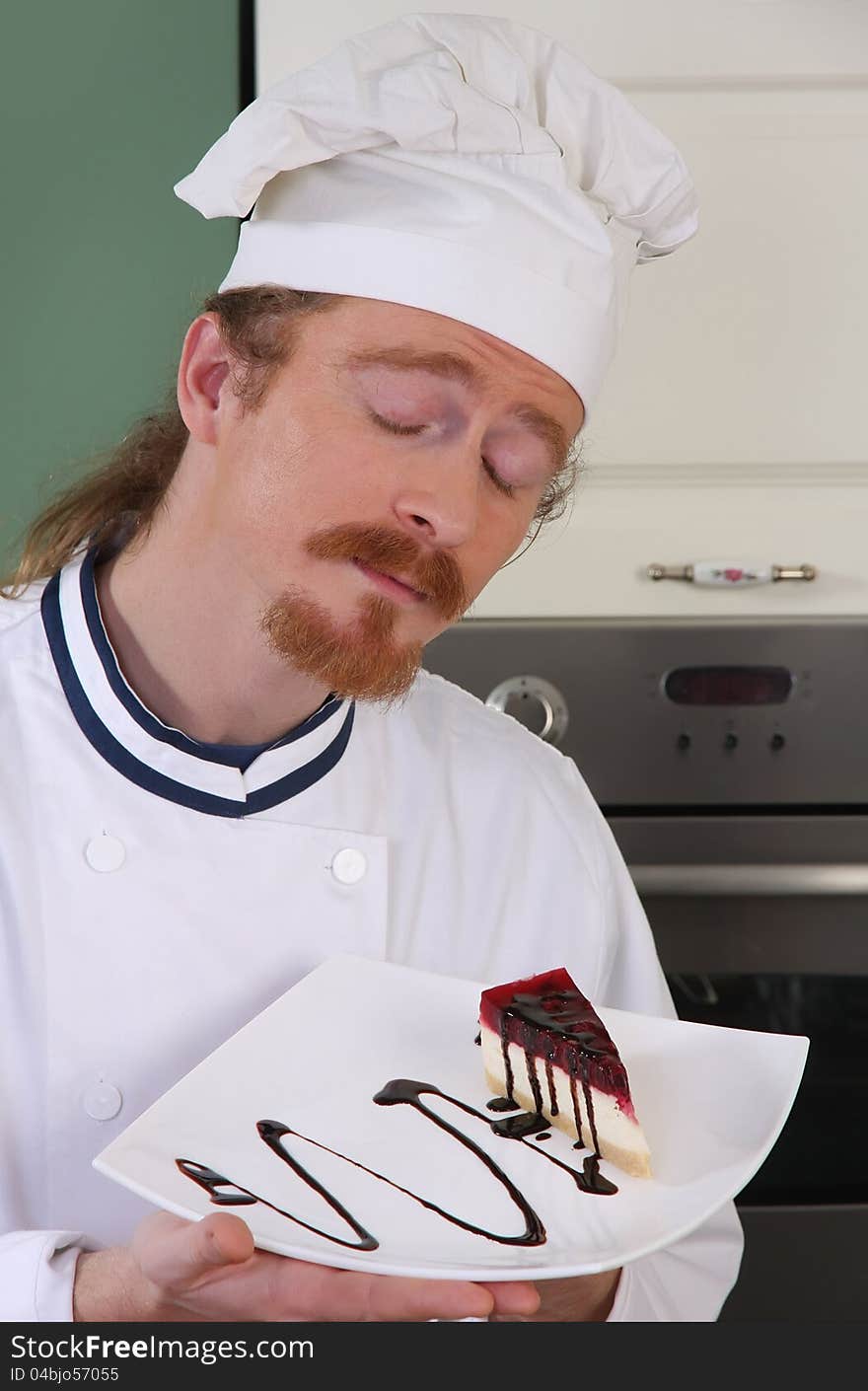 Funny young chef smelling a piece of cake with chocolate sauce