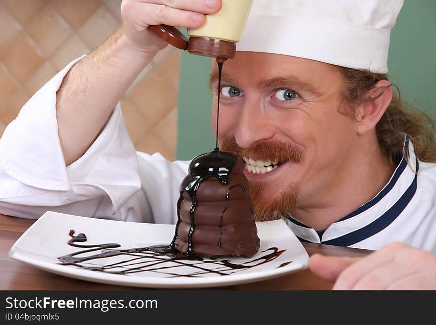 Funny young chef added chocolate sauce at piece of cake