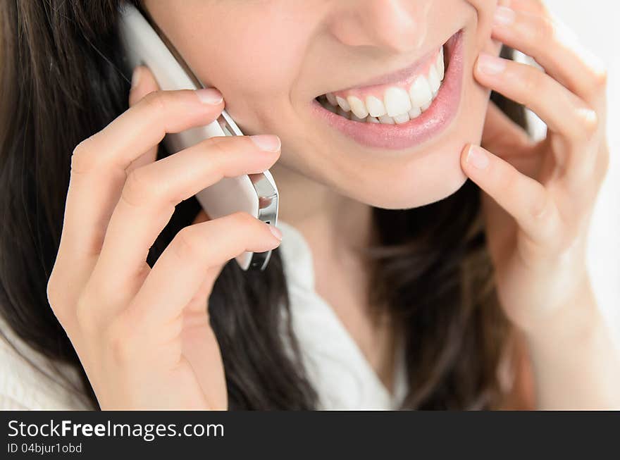 Close-up of a beautiful young woman talking on mobile phone intimately and smiling. Close-up of a beautiful young woman talking on mobile phone intimately and smiling