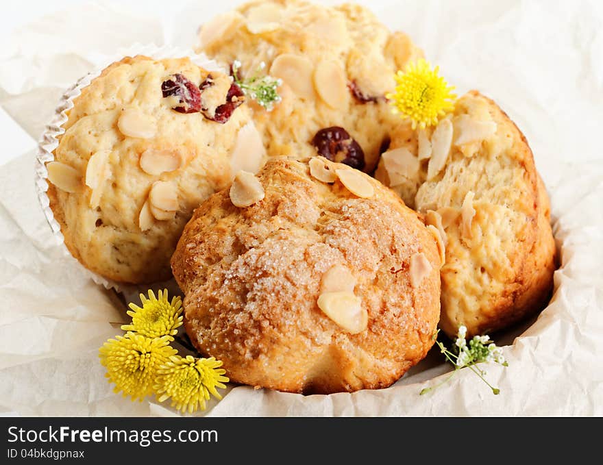 Almond muffins on paper basket and yellow flowers