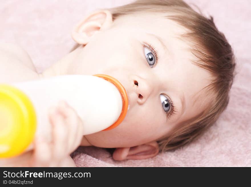 Little baby drinking milk, lying on pink towel, close up. Little baby drinking milk, lying on pink towel, close up