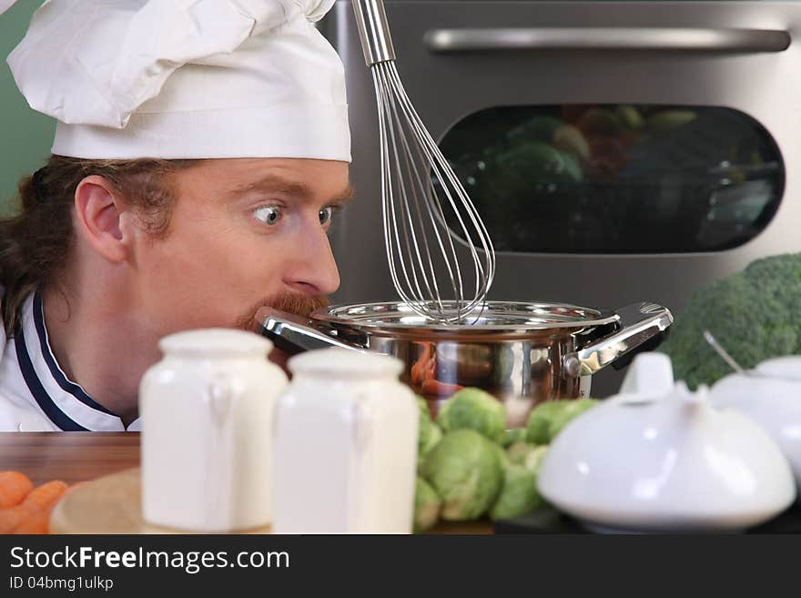 Funny young chef strange looking at pot