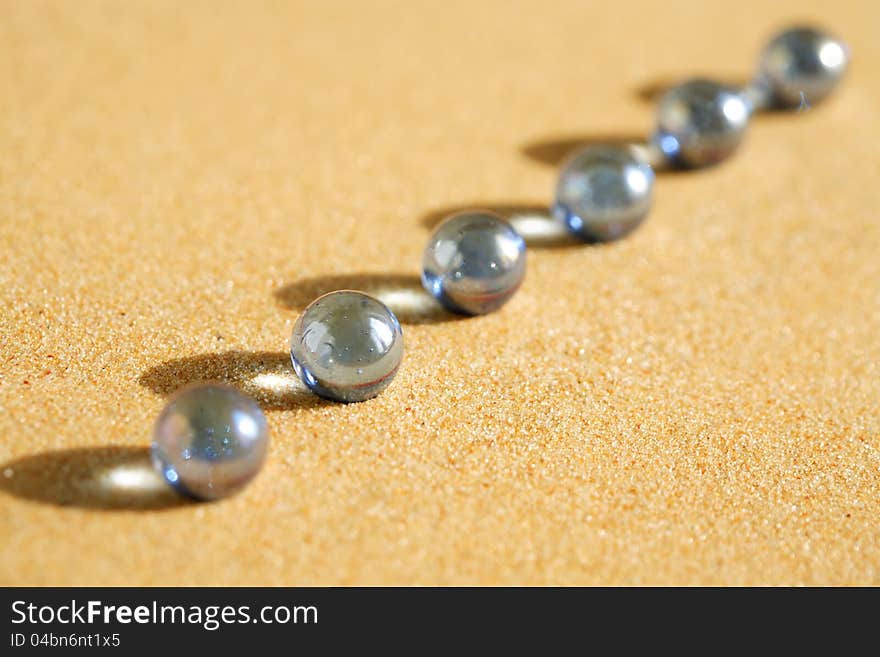 Abstract composition with few blue glass balls in a row on sand surface. Abstract composition with few blue glass balls in a row on sand surface