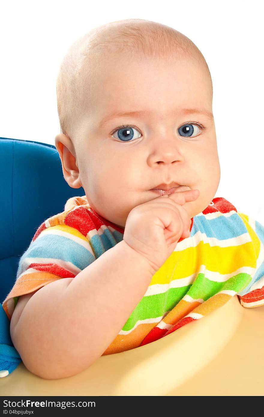 Little baby girl is sitting at the table with finger in the mouth. Little baby girl is sitting at the table with finger in the mouth