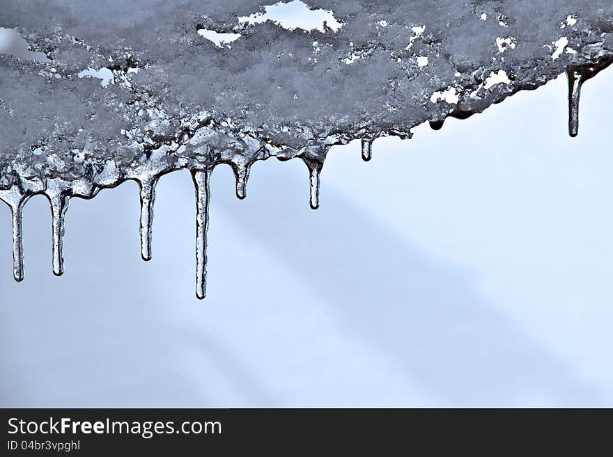 Closeup of icicles with blurred snow behind