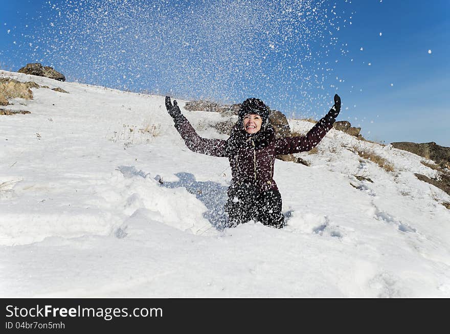 The beautiful young woman in mountain-skiing clothes has fun throwing upwards snow. The beautiful young woman in mountain-skiing clothes has fun throwing upwards snow