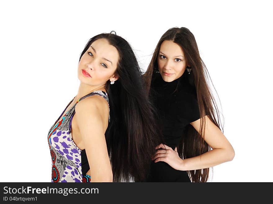 Two beautiful brunette girls look at camera inside white studio. Two beautiful brunette girls look at camera inside white studio