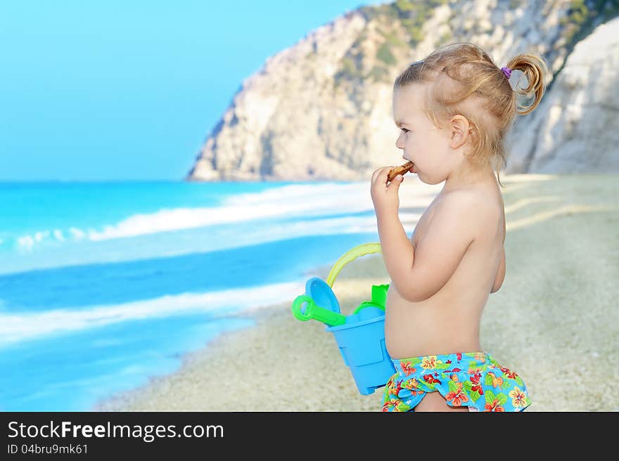 Happy child on the beach holding her toys, summer vacation concept