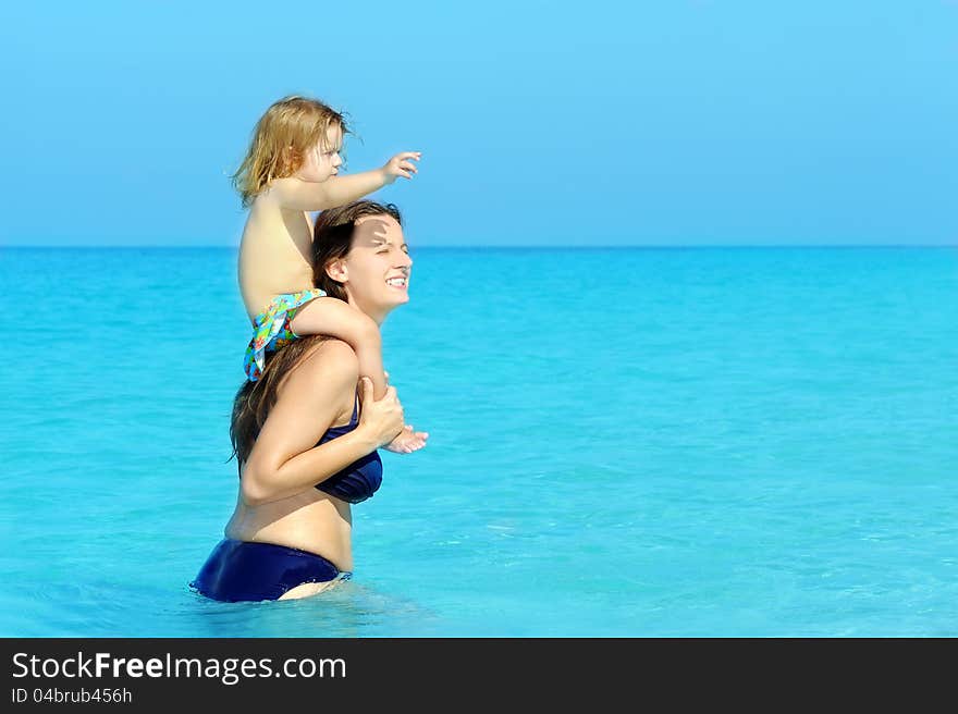 Happy child with her mother on the beach, summer vacation concept