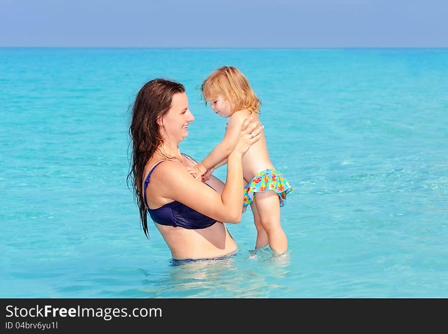 Happy mother with her daughter on the beach, summer vacation concept